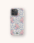 Introducing the Pink and Blue Coquette Flowers Eco-Friendly Biodegradable Phone Case, featuring a charming pattern of pink flowers, blue ribbons, and petite blue blooms on a light background. This sustainable phone case blends delicate style with eco-friendly design and is finished with a small black logo at the bottom.