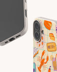 Two “Taste of Summer Eco-Friendly Biodegradable Phone Cases” in beige are featured: one displays the phone’s screen, while the other reveals the back decorated with vibrant illustrations of a lobster, lemon, drink, fish, and various seafood-themed designs. These cases combine stylish flair with sustainable, biodegradable materials.