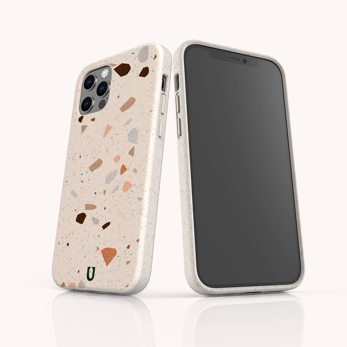 Two smartphones in beige terrazzo-patterned cases are shown: one faces forward displaying the screen, while the other reveals the Terrazzo Print Eco-Friendly Phone Case featuring multicolored specks and a small green horseshoe-shaped logo—combining unique style with sustainable phone protection.