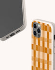 Two smartphones in biodegradable beige cases are showcased against a light background: one highlights the Brown Watercolour Checker Eco-Friendly Phone Case with its distinctive orange checkerboard pattern, while the other displays the phone’s plain front side.