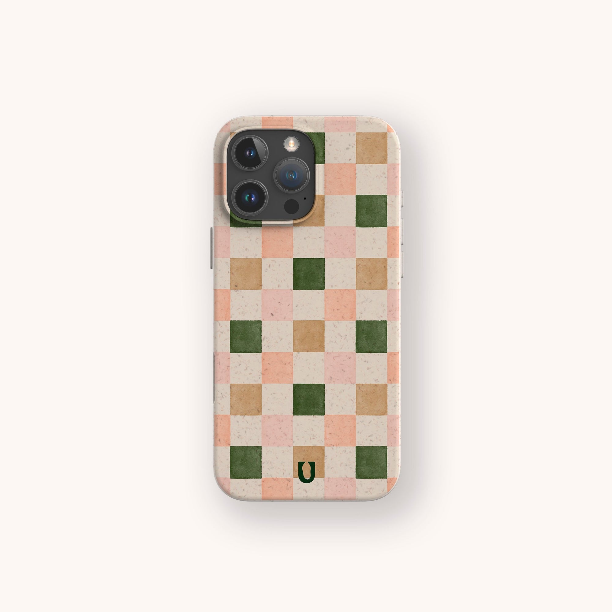 The Pink and Green Checker Eco-Friendly Phone Case features light pink, green, and beige checkered squares, a small black U-shaped logo at the bottom center, and fits iPhone and Samsung Galaxy. Made from vegan-friendly materials with an off-white background.