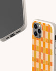 Two smartphones with beige cases are shown. One case, the Green and Orange Watercolour Checker Eco-Friendly Phone Case, features a watercolour checker pattern in orange and green shades; the other displays the phone’s screen and bottom ports. Both cases have a speckled texture and are compatible with iPhone and Samsung Galaxy models.