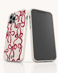 Two smartphones showcase the Burgundy Bow Ribbons Eco-Friendly Phone Case in beige: one displays the front screen, while the other reveals the back of the biodegradable case featuring a red ribbon bow design, all set against a white background.