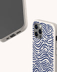 Two smartphones in off-white cases are displayed against a light background; one shows the screen, while the other features the Ocean Waves Eco-Friendly Phone Case design with a blue wavy line pattern on the back. Both cases are eco-friendly and have cutouts for ports, buttons, and cameras.