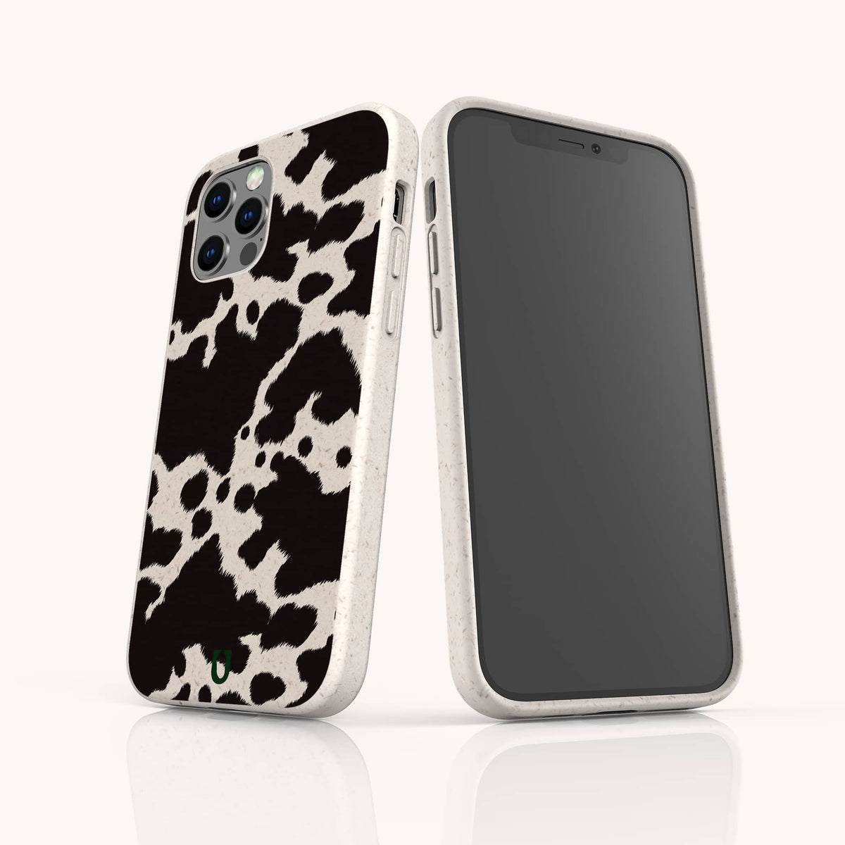 Two smartphones in white cases are showcased against a plain white background. One displays the stylish Cow Print Eco-Friendly Phone Case with its bold black and white cow pattern, while the other shows the front screen. Both cases are iPhone and Samsung compatible and made from eco-friendly materials.