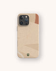 The Peachy Abstract Lines Biodegradable Phone Case boasts a minimalist, eco-friendly design in beige and brown with abstract geometric patterns, featuring the letter "U" at the bottom center. Crafted from biodegradable materials, it is displayed on a smartphone equipped with three camera lenses.
