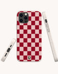 The Red and Pink Checker Eco-Friendly Biodegradable Phone Case is displayed from multiple angles against a light background, highlighting its red and pink checkered pattern, precise cutouts for buttons and ports, and a small horseshoe logo near the bottom.