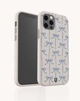The Blue Bow Ribbons Eco-Friendly Biodegradable Phone Case, featuring a repeating pattern of blue bows on a light-colored background, is displayed standing upright against a white backdrop, highlighting its charming and sustainable design.