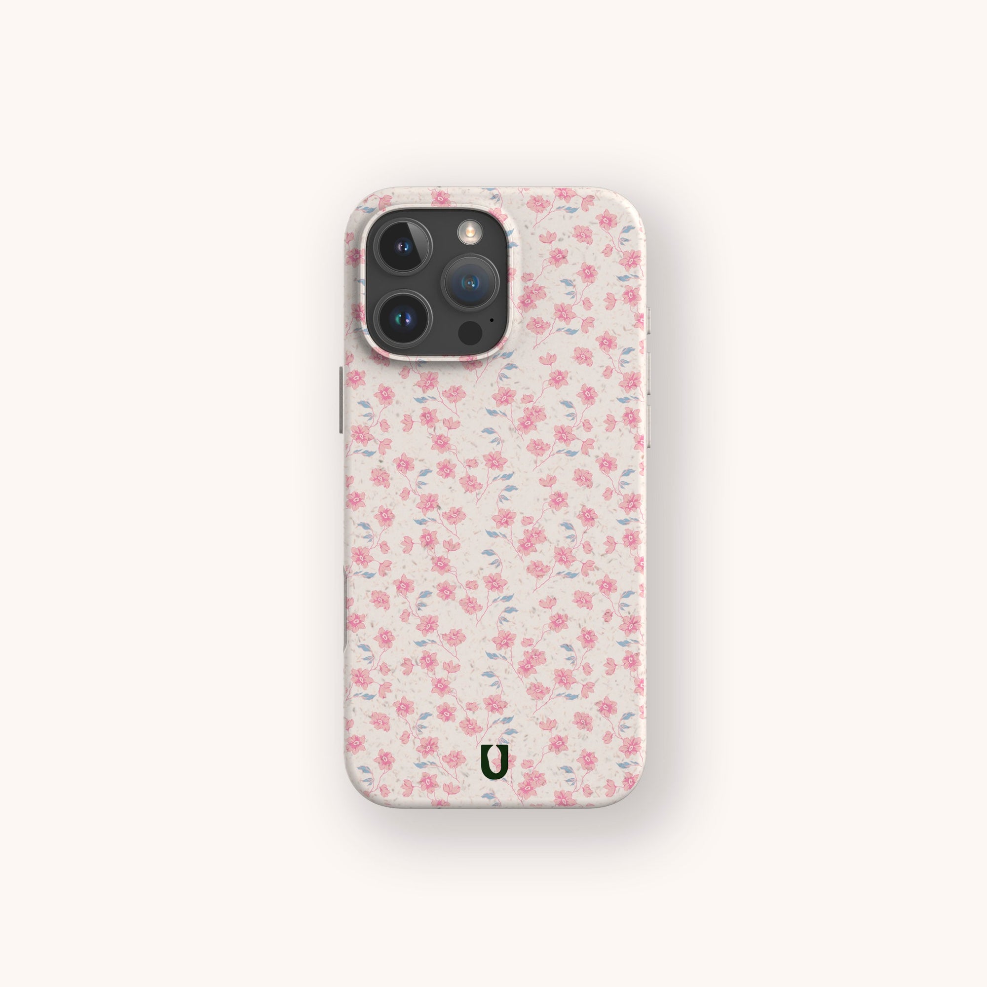 The Pink Ditsy Flowers Eco-Friendly Biodegradable Phone Case features a light pink and white floral pattern, scattered small roses, a green horseshoe-shaped logo, and fits phones with camera bumps—perfect for eco-conscious users.