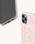 Two smartphones are shown, both with light-colored, speckled cases. One phone displays the screen, while the other highlights the Pink Ditsy Flowers Eco-Friendly Biodegradable Phone Case on the back. Both cases provide sustainable phone protection with precise cutouts for ports and buttons and feature a biodegradable case design.