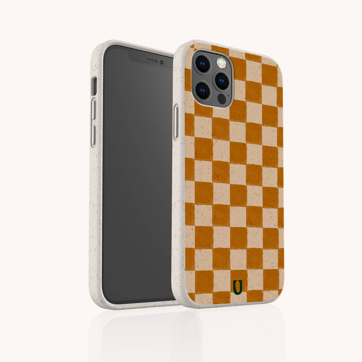 Brown Checker Eco-Friendly Phone Case shown on a smartphone, featuring a beige and orange checkerboard pattern with a small black and yellow logo at the bottom. The camera is clearly visible, while the case’s speckled biodegradable texture lends unique character and helps reduce environmental impact.
