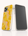 Two smartphones in white speckled Papaya Eco-Friendly Biodegradable Phone Cases; one reveals a yellow and pink abstract pattern on the back, while the other displays its front touchscreen. Both are positioned upright on a white reflective surface.