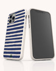 Two smartphones with white cases featuring horizontal navy blue stripes—the Navy Stripes Eco-Friendly Biodegradable Phone Case—are displayed upright on a white reflective surface. One phone showcases the striped back of the case, while the other reveals the front screen, emphasizing the stylish and sustainable design.