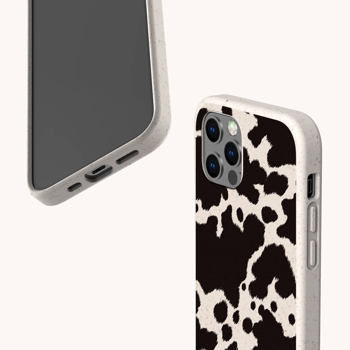 Two smartphones in protective cases; one features the Cow Print Eco-Friendly Phone Case in bold black and white, while the other is a plain beige eco-friendly case—both compatible with iPhone and Samsung devices—displayed on a plain, light background.