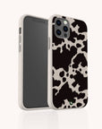 A Cow Print Eco-Friendly Phone Case featuring a black and white cow pattern is displayed from both front and back angles against a plain white background. The case has a textured look, offers full coverage for all sides of the phone, and is compatible with iPhone and Samsung models.