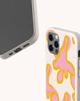 Two smartphones in Pink Abstract Flowers Eco-Friendly Phone Cases. The beige cases feature yellow and pink abstract splashes, creating a playful look inspired by floral designs. Phones are angled to display the case pattern and camera, with screens turned away on a plain background.