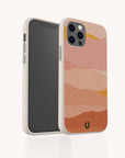 Smartphone in the Mountains Eco-Friendly Phone Case, which features a multicolored, abstract wavy design in pink, peach, and orange tones. The case has a speckled texture, a small green logo at the bottom, and is compatible with both iPhone and Samsung devices.