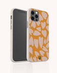 The Orange Hearts Eco-Friendly Biodegradable Phone Case is showcased on a smartphone, displaying its vibrant orange color and pink heart pattern. The phone is pictured from both the front and back, emphasizing the camera area and the case’s textured, sustainable edges.