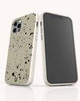 Two smartphones in beige Grunge Eco-Friendly Phone Cases with black paint splatters stand upright—one displaying the back and the other showcasing the front screen—against a white background.
