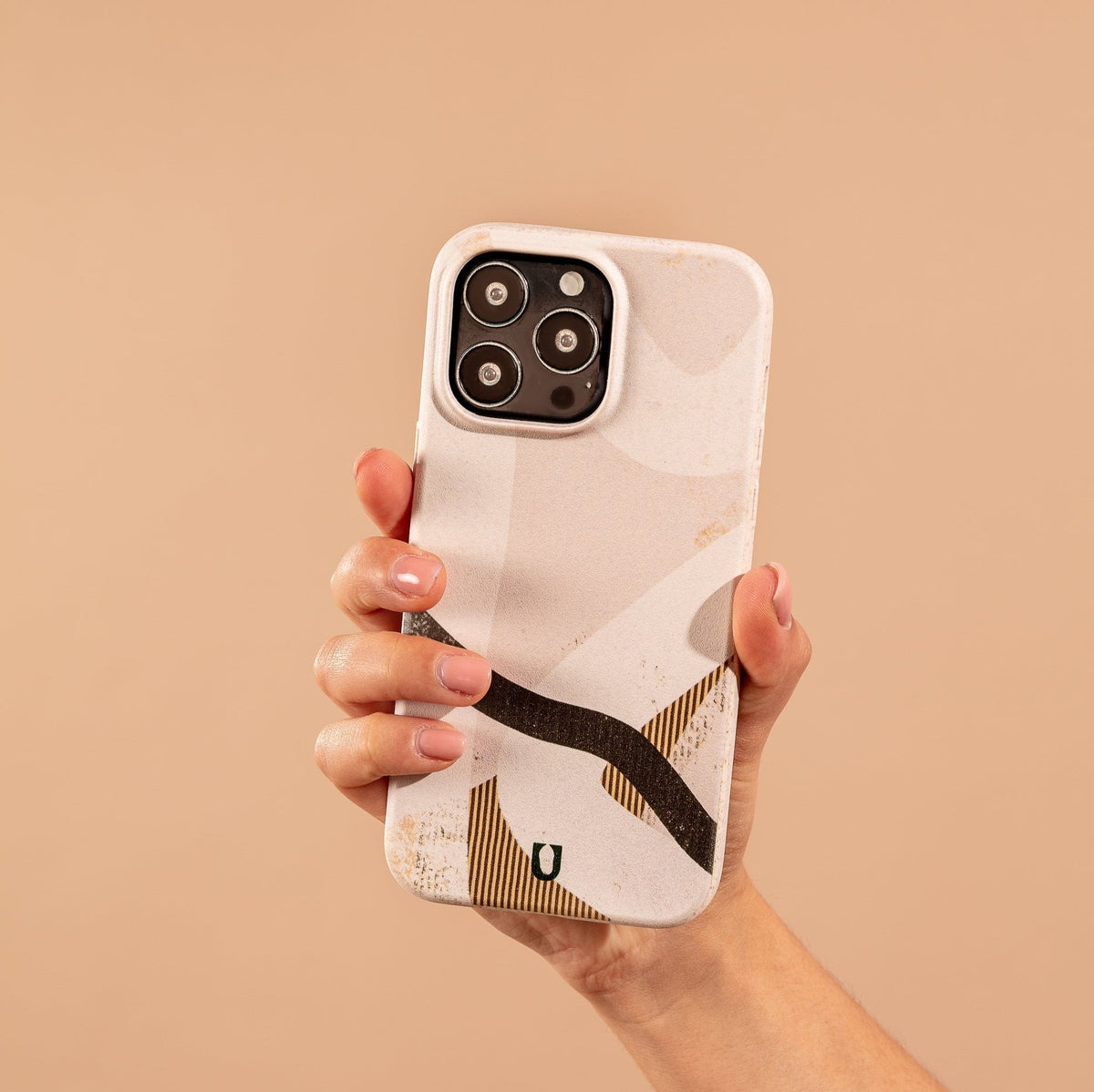 A hand holding the Beige Abstract Eco-Friendly Phone Case—a minimalist phone case with a beige abstract pattern—set against a matching beige background.