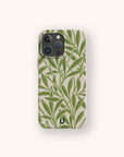 Introducing the Willow Eco-Friendly Phone Case — a plant-based case adorned with a green leafy pattern on a light beige background, shown upright on a simple off-white surface. Perfect for iPhone and Samsung Galaxy users who value both style and sustainability.