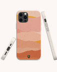 Three views of a phone in the Mountains Eco-Friendly Phone Case, featuring an abstract, wavy desert design in pink, peach, and ochre tones. The case is light speckled beige with rounded edges and simple button placements, and is compatible with both iPhone and Samsung models.