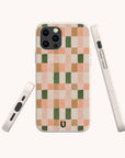 The Pink and Green Watercolour Eco-Friendly Phone Case, featuring a checkered pattern in pink, green, beige, and orange hues with a small horseshoe design near the bottom, is displayed from three angles against a light background.