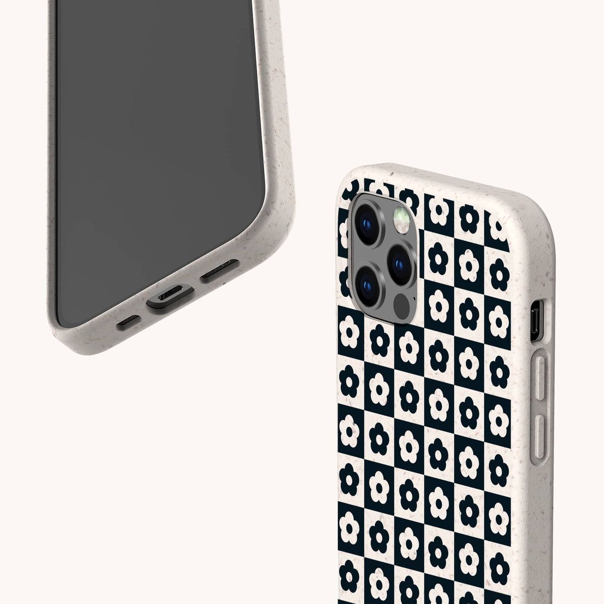 Two smartphones with off-white cases; one case is the Black Flower Checker Eco-Friendly Phone Case, which features a checkerboard design with black and white flowers, while the other phone displays its screen and port details. Both are set against a plain, light background.