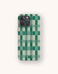 The Green Watercolour Checker Eco-Friendly Phone Case features a green and white checkerboard design, is biodegradable, fits both iPhone and Samsung Galaxy models, and includes a small black horseshoe-shaped logo near the bottom center.