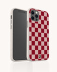 A Red and Pink Checker Eco-Friendly Biodegradable Phone Case featuring a white speckled, red and pink checkerboard design is displayed on a smartphone, shown from both the front and back against a white background.