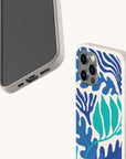 Two smartphones with beige speckled, compostable phone cases are displayed on a white background; one case is the Sea Bed Eco-Friendly Phone Case, featuring a blue and teal abstract leaf pattern inspired by the ocean, while the other is plain. Both eco-friendly phone cases are shown from different angles.