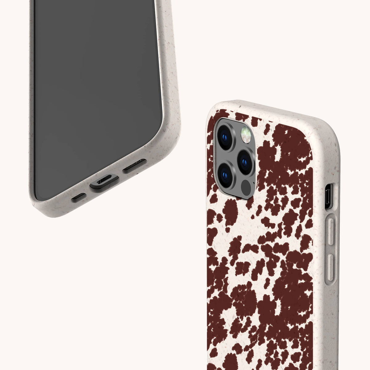 Two smartphones with beige cases—Brown Cow Print Eco-Friendly Phone Case designs; one showcases a brown cow print splatter pattern, while the other remains plain. Compatible as iPhone and Samsung Galaxy case options, both feature precise cutouts for ports and camera. The phones are angled to display both front and back views.