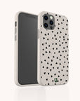 The Black Hearts Eco-Friendly Phone Case features a white background adorned with scattered small black hearts, perfectly fitted on a smartphone with triple rear cameras and displayed from both the front and back against a light surface. This sustainable phone case blends a chic heart pattern with environmentally conscious materials, offering stylish and planet-friendly protection.