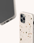 Two smartphones in Brown Terrazzo Eco-Friendly Phone Cases. One phone displays the screen and charging port, while the other showcases the back, emphasizing the mosaic brown terrazzo design, camera, and side buttons. Made as an eco-friendly accessory, this case features a light background for a minimalist aesthetic.