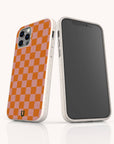 Two smartphones in white speckled cases are displayed; one reveals the front screen, while the other features the Orange Checker Eco-Friendly Phone Case, showcasing a vibrant pink and orange checkerboard design with three camera lenses. These eco-friendly cases combine standout style with sustainability for your device.