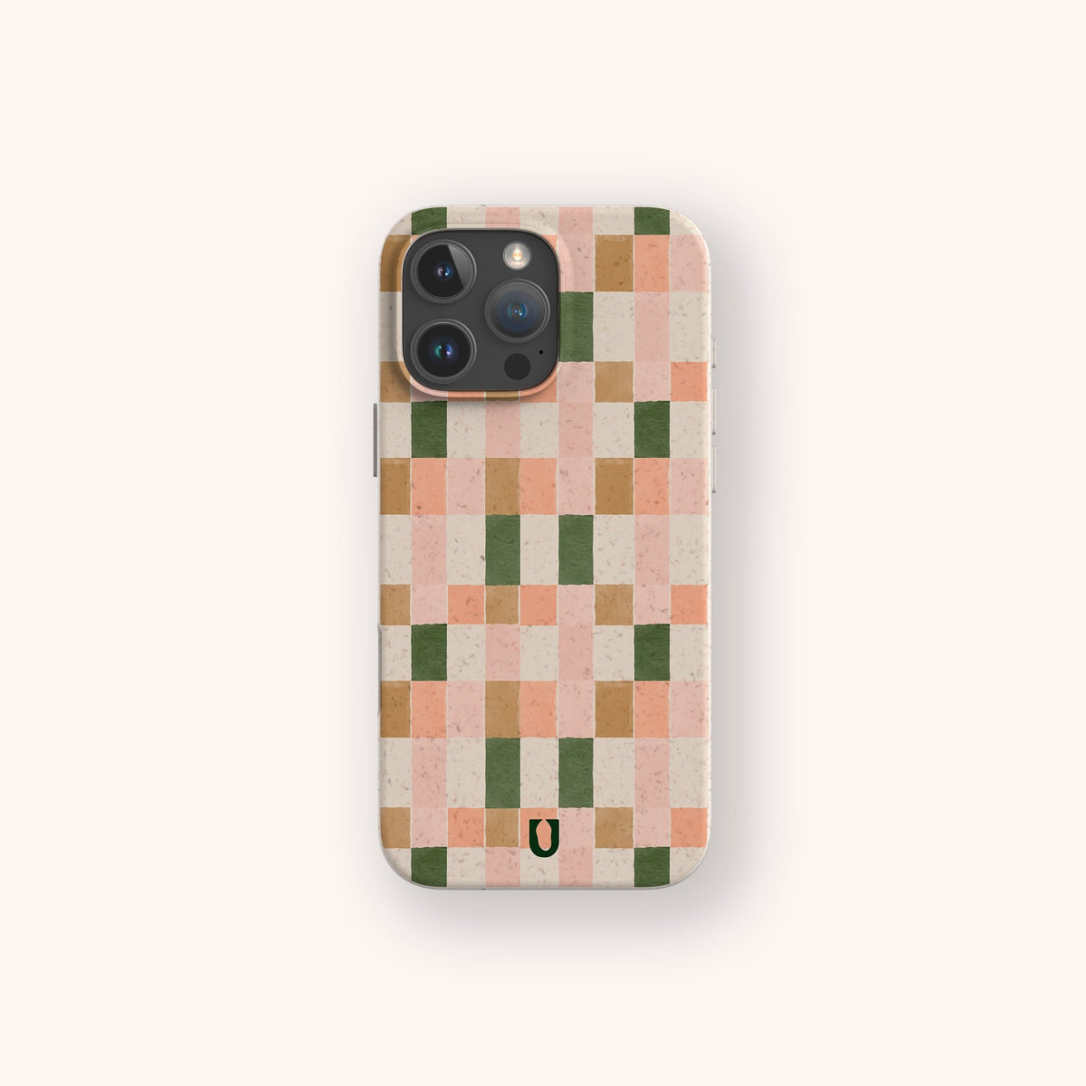 The Pink and Green Watercolour Eco-Friendly Phone Case features a pink, peach, green, and tan checkerboard pattern with a small black horseshoe logo at the bottom center.