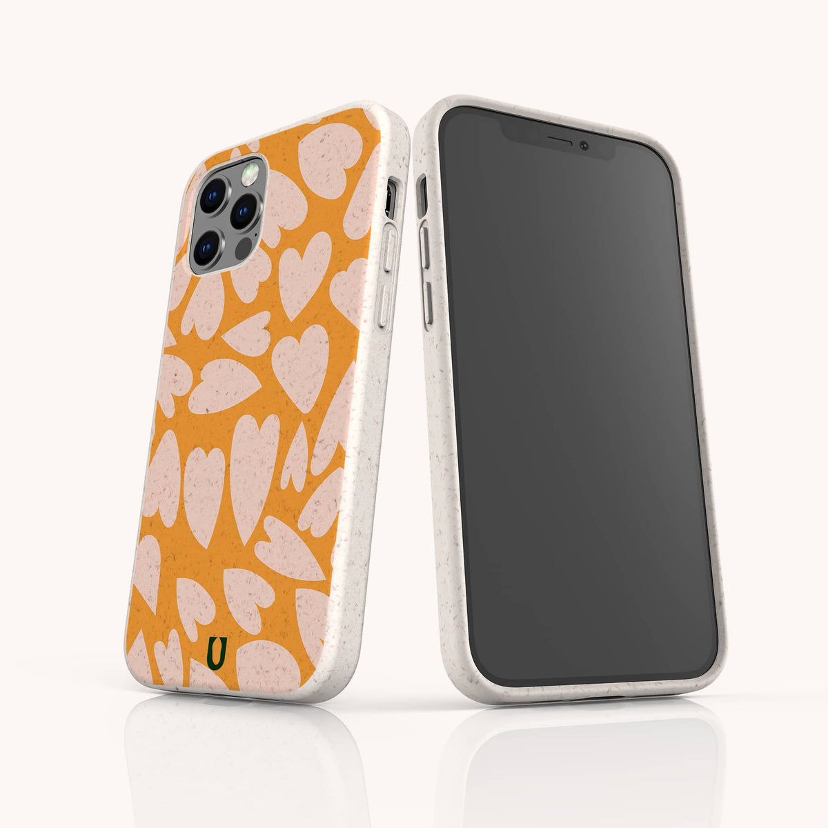 Two smartphones in white, each fitted with the Orange Hearts Eco-Friendly Biodegradable Phone Case featuring an orange and pink heart pattern. One phone highlights the patterned back of this sustainable case, while the other displays its plain black screen and side buttons. The background is white.