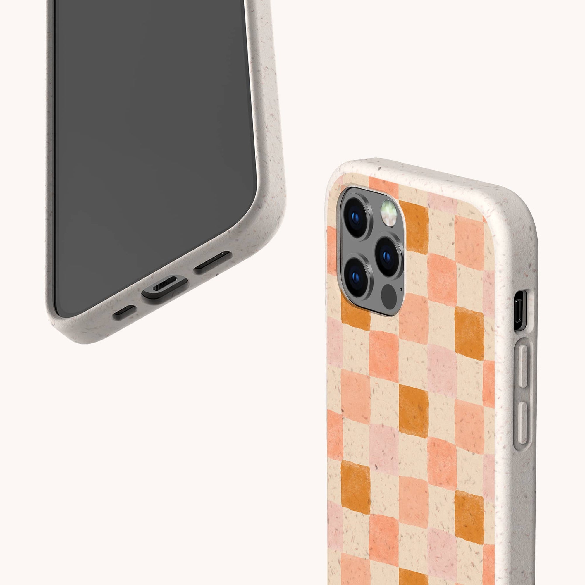 Two smartphones with eco-friendly phone cases: one is the Pink Watercolour Checker Eco-Friendly Phone Case, featuring a pink and orange checkerboard design; both fit iPhone and Samsung Galaxy and have visible buttons, speaker, and charging port.