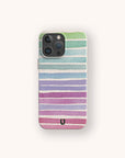 A smartphone with the Winter Rainbow Eco-Friendly Phone Case, which features horizontal watercolor stripes in green, blue, purple, and pink on an off-white background and a small black U-shaped symbol at the bottom.