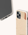 Two smartphones in beige, speckled Abstract Strokes Eco-Friendly Biodegradable Phone Cases are shown. One phone displays its screen and charging port, while the other reveals the back, dual camera lenses, and a subtle wooden accent on the case. These sustainable cases combine reliable protection with an eco-conscious design—ideal for anyone who values both style and environmental responsibility.